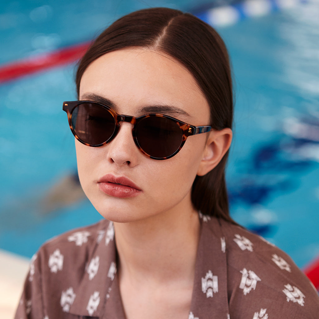 a woman wearing sunglasses is sitting on a cell phone 